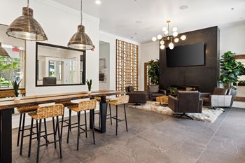 a bar area with stools and chairs and a large screen tv on the wall